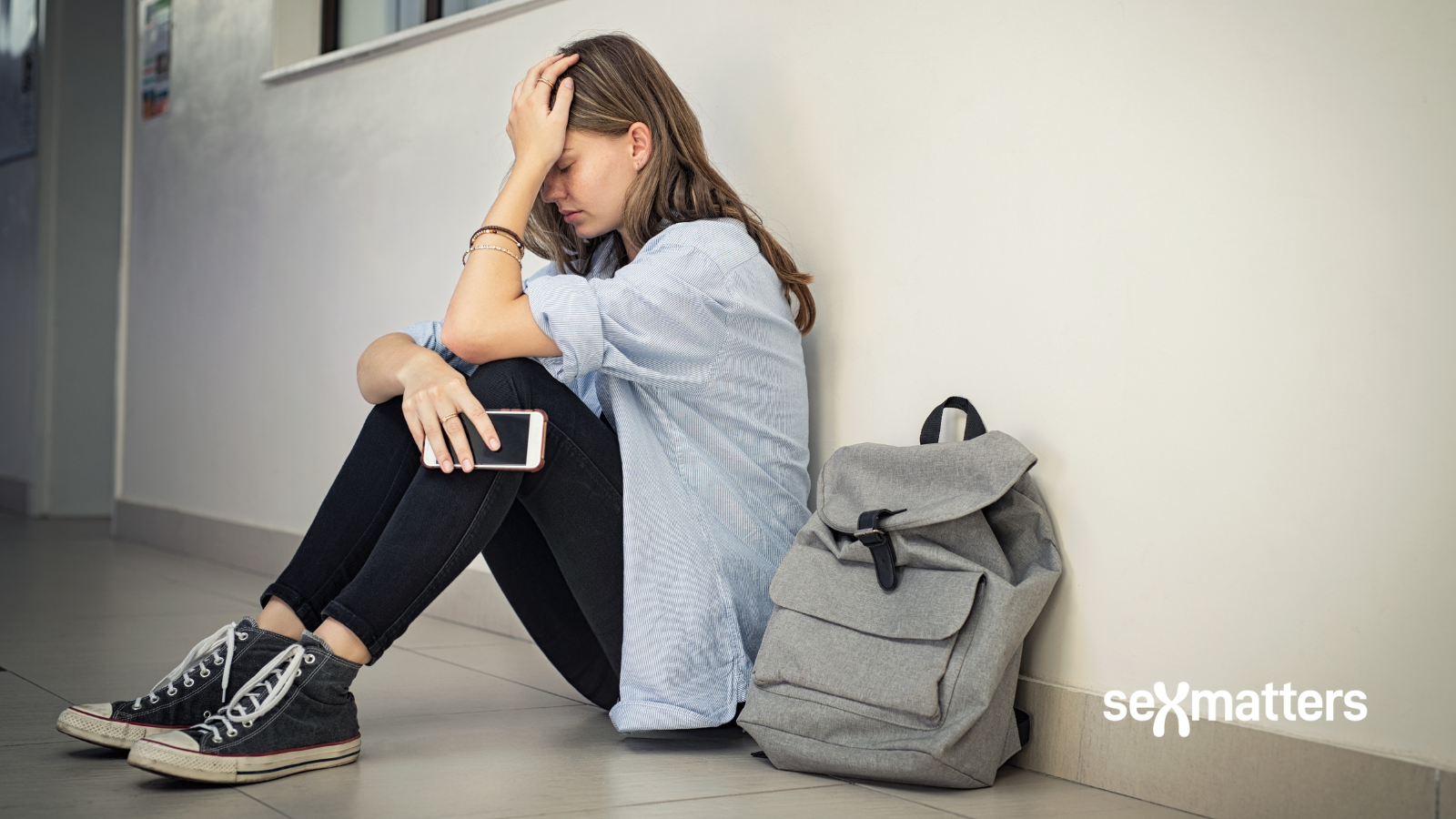 Universities – female student sitting in corridor with head in hands
